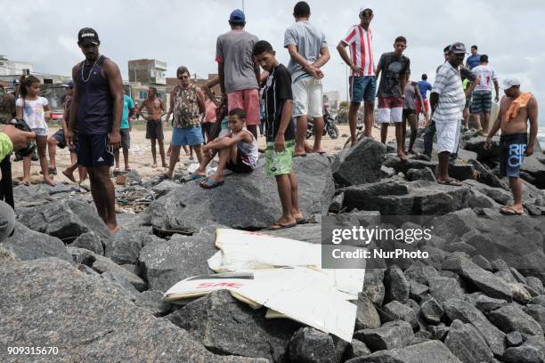 Residents of the site observe a piece of the helicopter that the sea threw on the rocks, near the scene of the accident, in Recife, Northeast Brazil,...