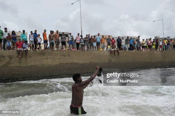 Resident of the place near the accident enters the sea to rescue parts of the helicopter, in Recife, Northeast Brazil, on January 23, 2018. A...