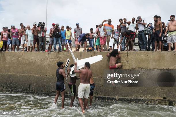 Residents help firefighters and rescue a part of the helicopter's propeller, in Recife, Northeast Brazil, on January 23, 2018. A helicopter from the...