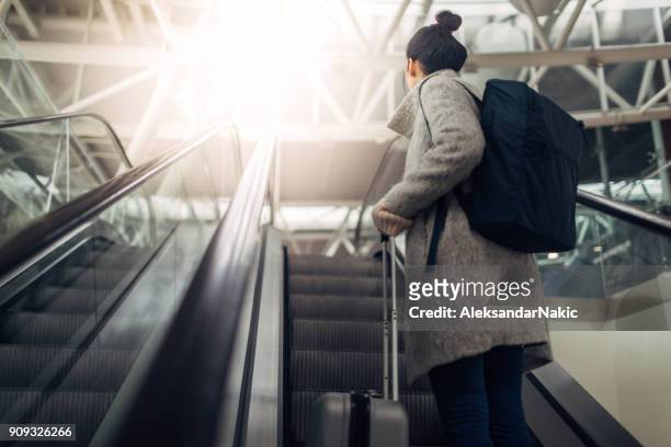 mujer joven en el aeropuerto, en la escalera mecánica - equipaje de mano fotografías e imágenes de stock