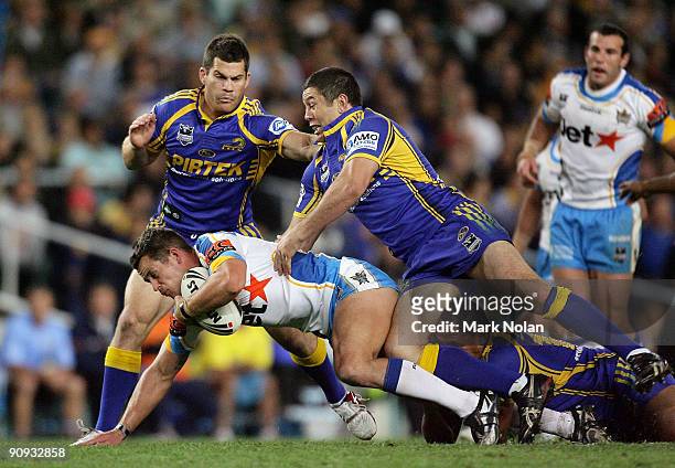 Ashley Harrison of the Titans is tackled by Nathan Cayless during the first NRL semi final match between the Parramatta Eels and the Gold Coast...