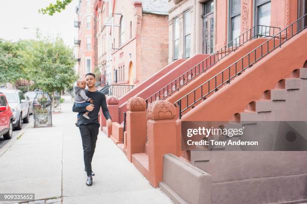 Young father walking with infant daughter in city neighborhood