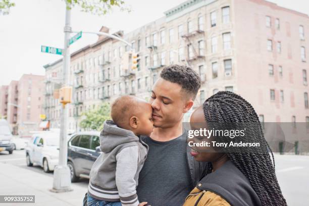 Young mother and father walking with infant daughter in city neighborhood