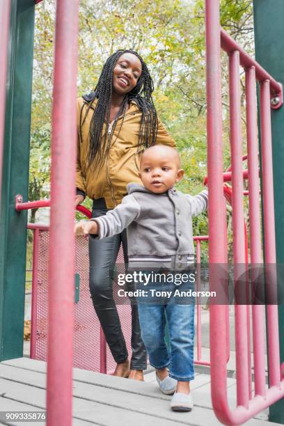 Young mother playing with infant daughter in city park