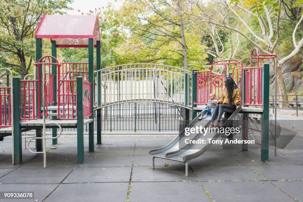 Young mother playing with infant daughter in city park