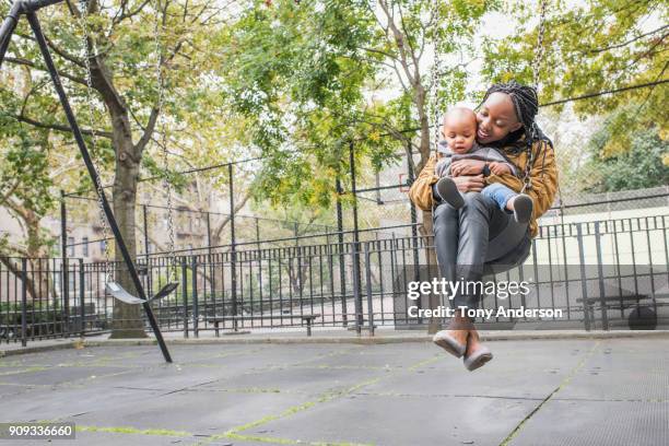 Young mother playing with infant daughter in city park