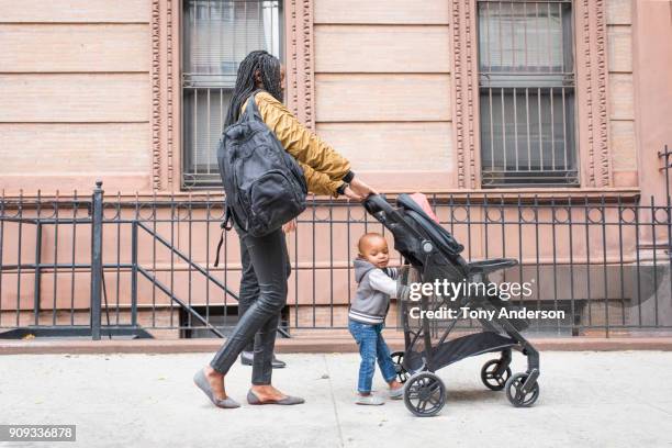 young mother walking with infant daughter in the city - mother stroller stock pictures, royalty-free photos & images