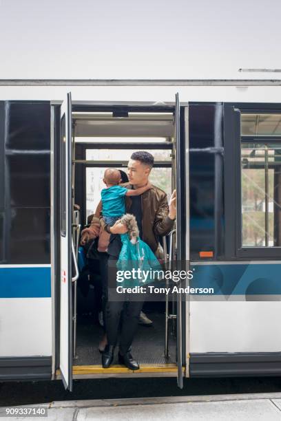 Young mother father and infant exiting city bus