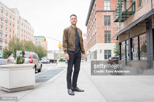 young man standing on city sidewalk - black jacket photos et images de collection
