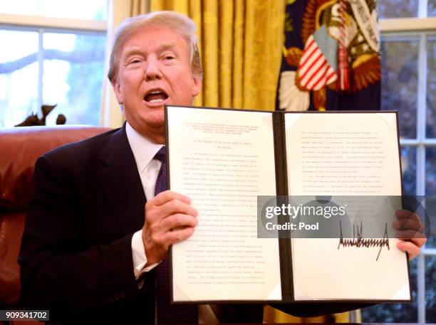 President Donald Trump holds up a Section 201 action after signing it in the Oval Office, at the White House, January 23 in Washington, DC. The...