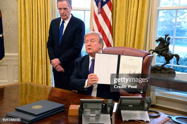 President Donald Trump displays a Section 201 action as US Trade Representative Robert Lighthizer witnesses, in the Oval Office, at the White House,...