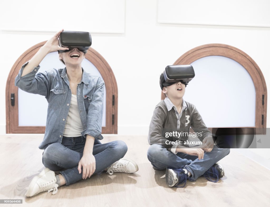 Mother and son playing with virtual reality glasses in living room