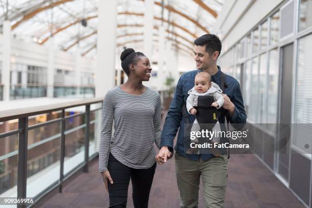 Padres felizes paseando con su bebé en un centro comercial