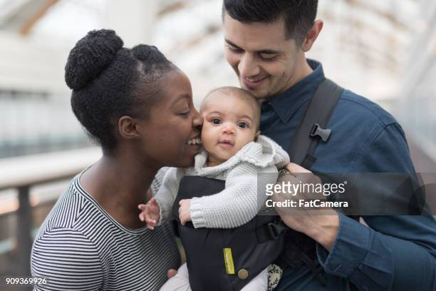 adoring parents with their baby in a shopping mall - multiracial person stock pictures, royalty-free photos & images