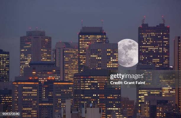 super moon rising between office towers - light show spectacular stock pictures, royalty-free photos & images