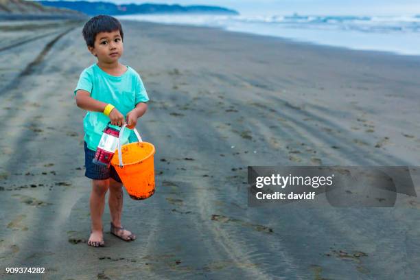 young boy at dusk with a bucket and lantern on a beach - maori fishing stock pictures, royalty-free photos & images