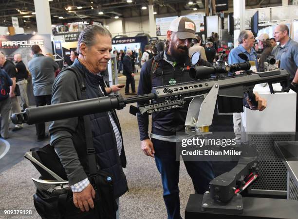 Benjamin Aquilina and Eros Adragna, both of Texas, look at a .50 caliber semi-automatic Browning Machine Gun at the Barrett booth at the 2018...