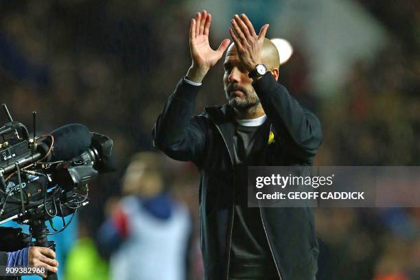 Manchester City's Spanish manager Pep Guardiola applauds supporters on the pitch as they celebrate after the English League Cup semi-final, second...
