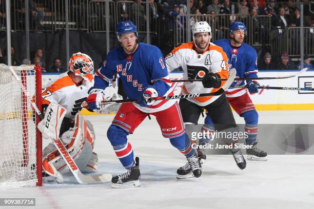 Peter Holland of the New York Rangers skates against Andrew MacDonald and Brian Elliott of the Philadelphia Flyers at Madison Square Garden on...