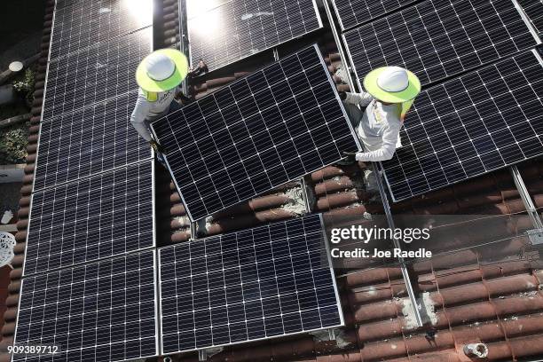 Roger Garbey and Andres Hernandez , from the Goldin Solar company, install a solar panel system on the roof of a home a day after the Trump...