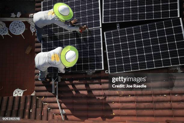 Roger Garbey and Andres Hernandez, from the Goldin Solar company, install a solar panel system on the roof of a home a day after the Trump...