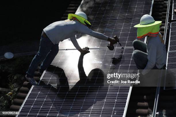 Roger Garbey and Andres Hernandez , from the Goldin Solar company, install a solar panel system on the roof of a home a day after the Trump...