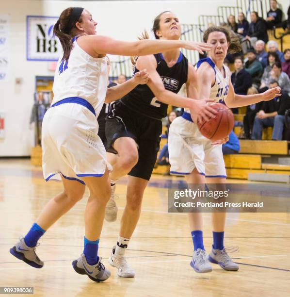 University of New Englands Ashley Coneys drives toward the basket, between St. Josephs defenders Emily Benway, and Kelsi McNamara during womens...