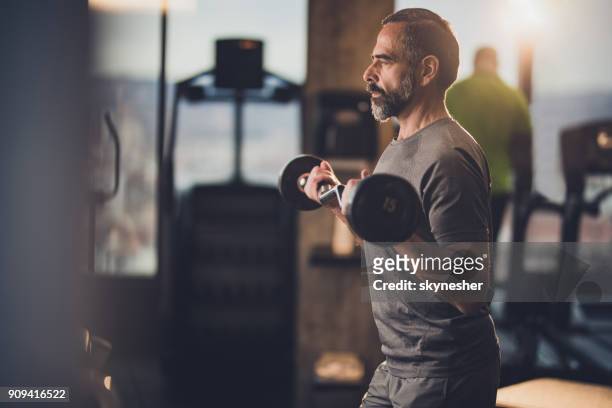 active senior man having strength exercise with barbell in a gym. - health club stock pictures, royalty-free photos & images