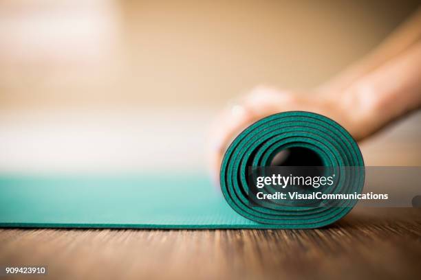 femme retroussant tapis d’yoga. - tapis de sol photos et images de collection