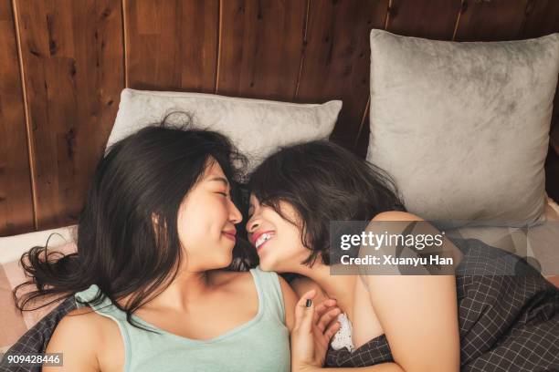 lesbian couple laughing in bed - lesbian stockfoto's en -beelden