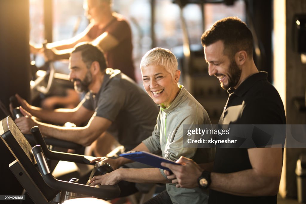 Glückliche senior Frau Spaß mit ihrer Trainerin auf spinning-Klasse in ein Fitness-Studio.