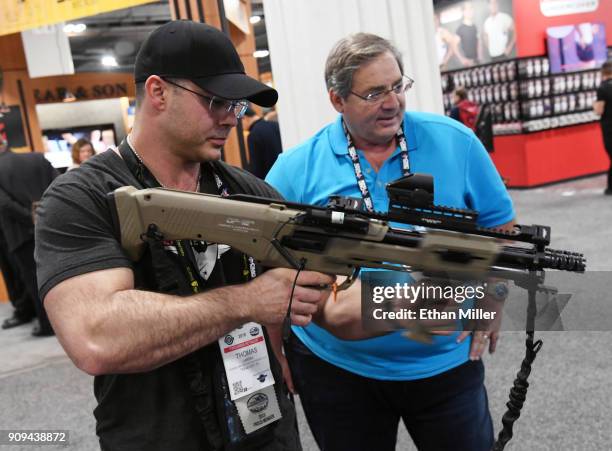 Thomas Larosa and Michael T. Godinich, both of Texas, look at a Standard Manufacturing Co. DP-12 double pump-action shotgun at the 2018 National...