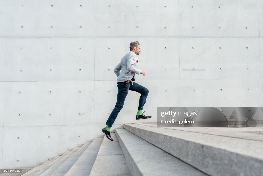 Elegante bärtigen Geschäftsmann laufen Treppen im freien