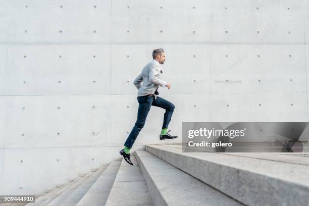 elegant bearded businessman running up stairs outdoors - businessman running stock pictures, royalty-free photos & images