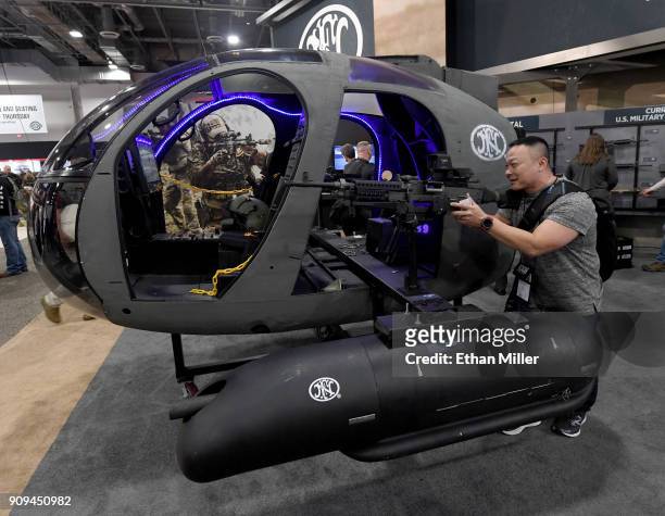 Hai Hong of Texas poses with a Pod HMP400 with M3P .50 caliber, fully automatic heavy machine gun mounted on a helicopter frame at the FN America...