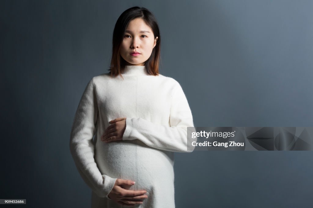 Zwangere vrouw aanraken van de buik over grijze achtergrond