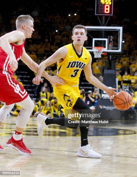 Guard Jordan Bohannon of the Iowa Hawkeyes brings the ball down the court during the second half past guard T.J. Schlundt of the Wisconsin Badgers on...