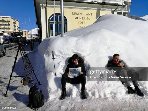 Two journalists rest on the snow on the opening day the World Economic Forum 2018 annual meeting on January 23, 2018 in Davos, Switzerland. The World...