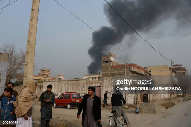 Afghan civilians gather on a street next to a plume of smoke coming from the area around an office of the British charity Save the Children during an...