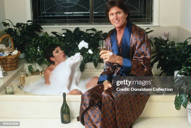 Athlete Bruce Jenner and his partner Kris Jenner, formerly Kris Kardashian, share a bottle of Dom Perignon over a bubble bath, circa 1991.