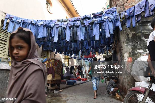 Muslim girls walks through an alley as used pairs of jeans are hung to dry before they are sold in a second-hand clothes market on January 23,2018 in...