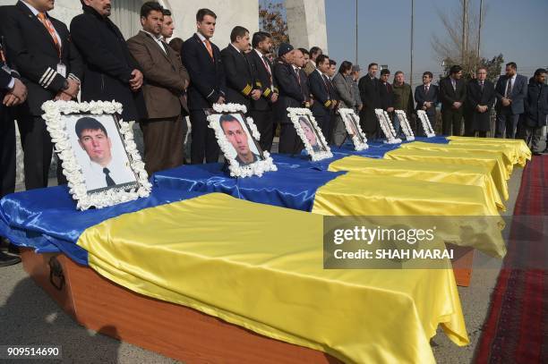 Kam Air employees stand over their colleague's coffins, all Ukrainian employees of the Afghan airline, at a ceremony at Kabul International Airport...