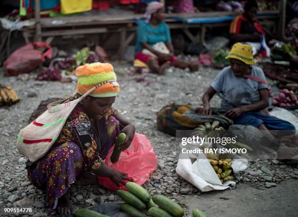 Papuan women sell fruit and vegetables on a street market in Timika in Indonesia's easternmost Papua province on January 24, 2018. / AFP PHOTO / Bay...