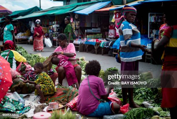 Papuan women sell fruit and vegetables on a street market in Timika in Indonesia's easternmost Papua province on January 24, 2018. / AFP PHOTO / Bay...