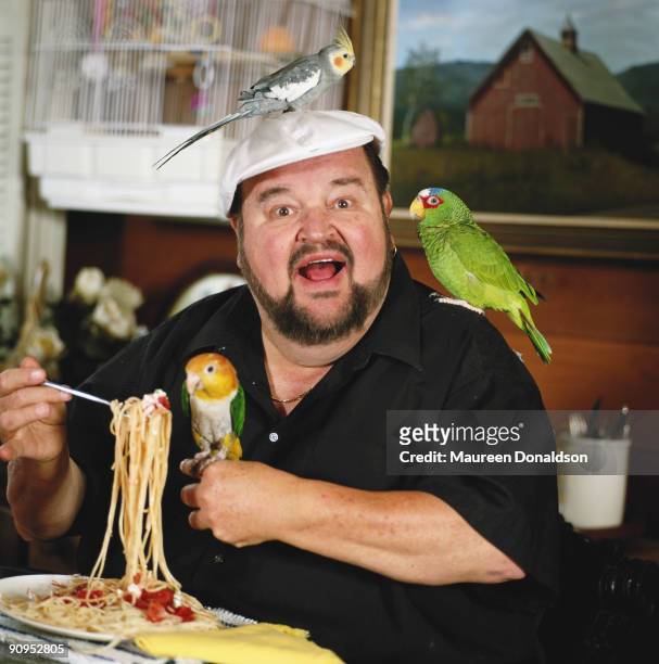 American actor, comedian and cookery writer Dom DeLuise with a homemade pasta dish and some pet birds, circa 1998.