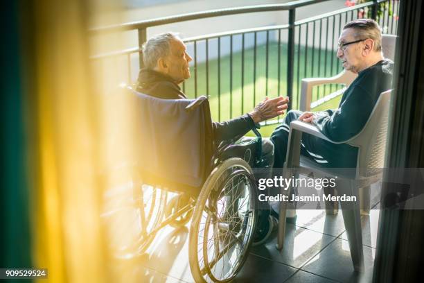 two senior men speaking together outdoor - man crutches stock pictures, royalty-free photos & images