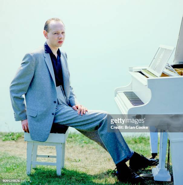 Joe Jackson posing with a white grand piano on the cliff above Folkestone Harbour on the 4th June 1982 during the making of a promotional film for...