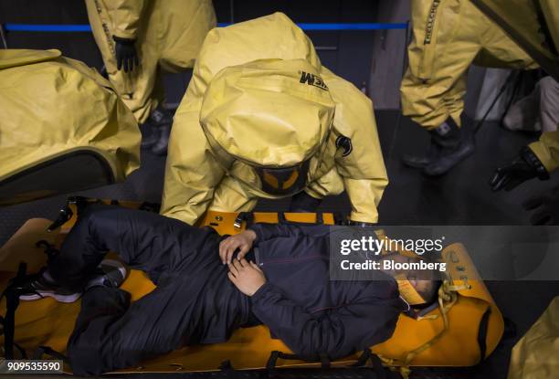 Members of the Chiba City Fire Department wearing protective suits carry a participant acting injured during a sarin attack drill at the Makuhari...