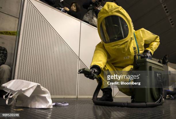 Member of the Chiba City Fire Department wearing a protective suit uses a detector while participating in a sarin attack drill at the Makuhari Messe...