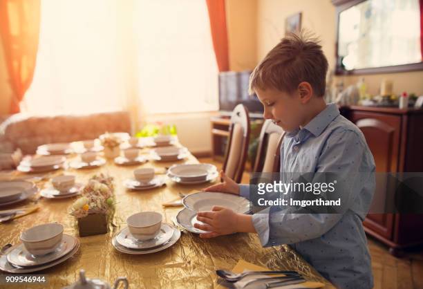 little boy helping in setting the table for traditional easter breakfast - setting the table stock pictures, royalty-free photos & images